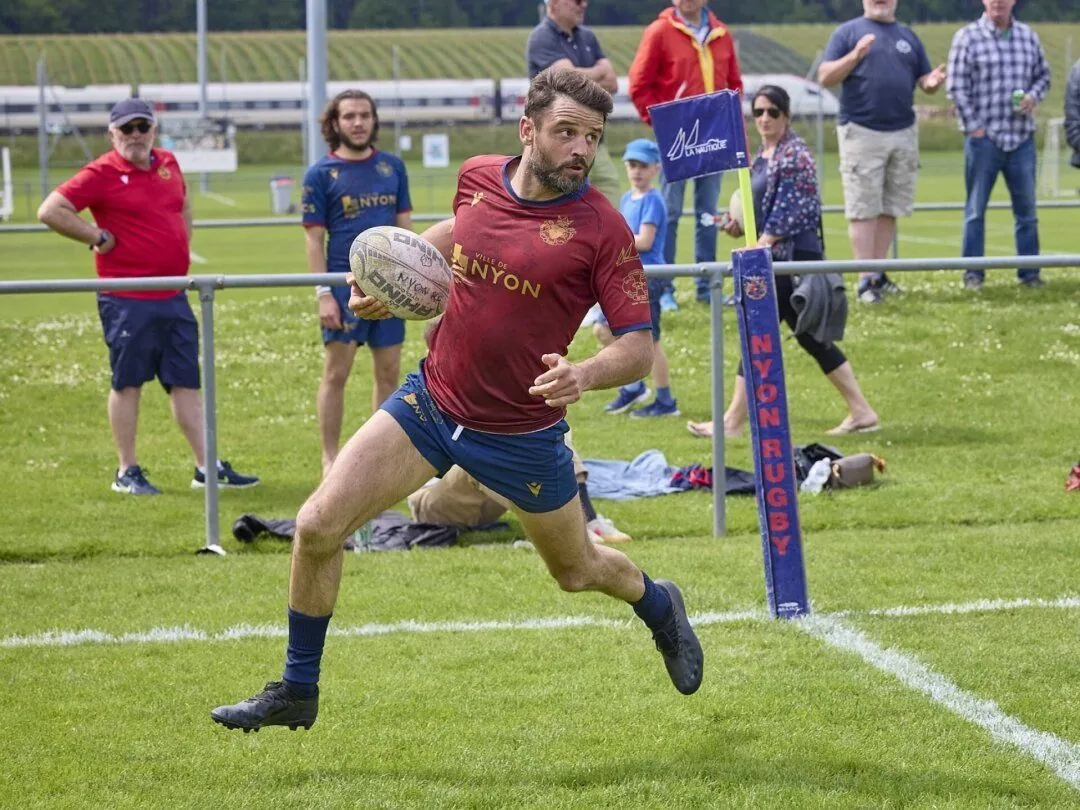 Un joueur de la première équipe en maillot rouge court ballon en main le long de la ligne